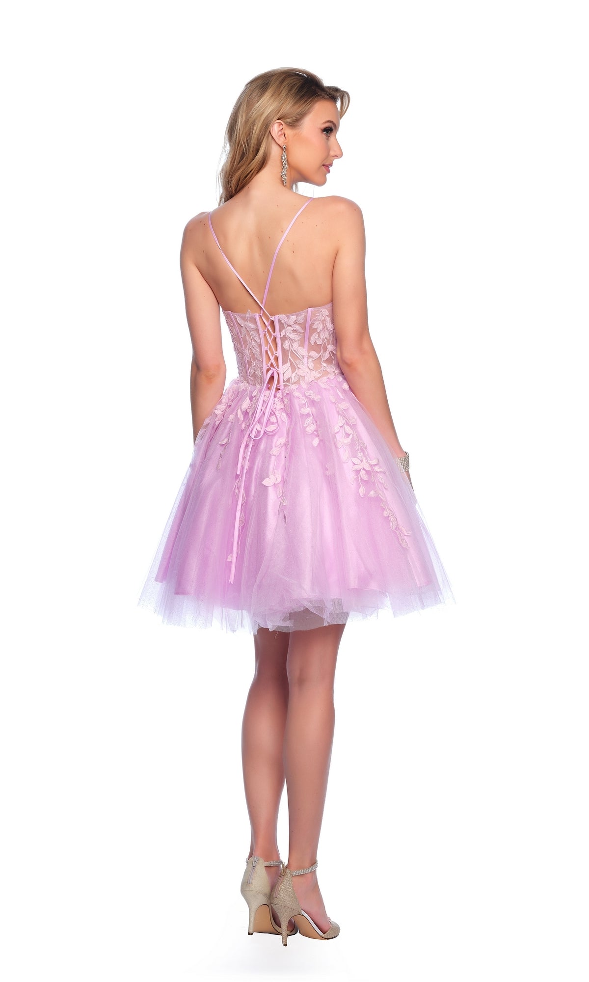 A woman stands facing away, wearing the Purple Homecoming Dress: Dave & Johnny 11750—a short, sleeveless, fit-and-flare dress with a lace-up back and floral detailing—paired with beige heels.